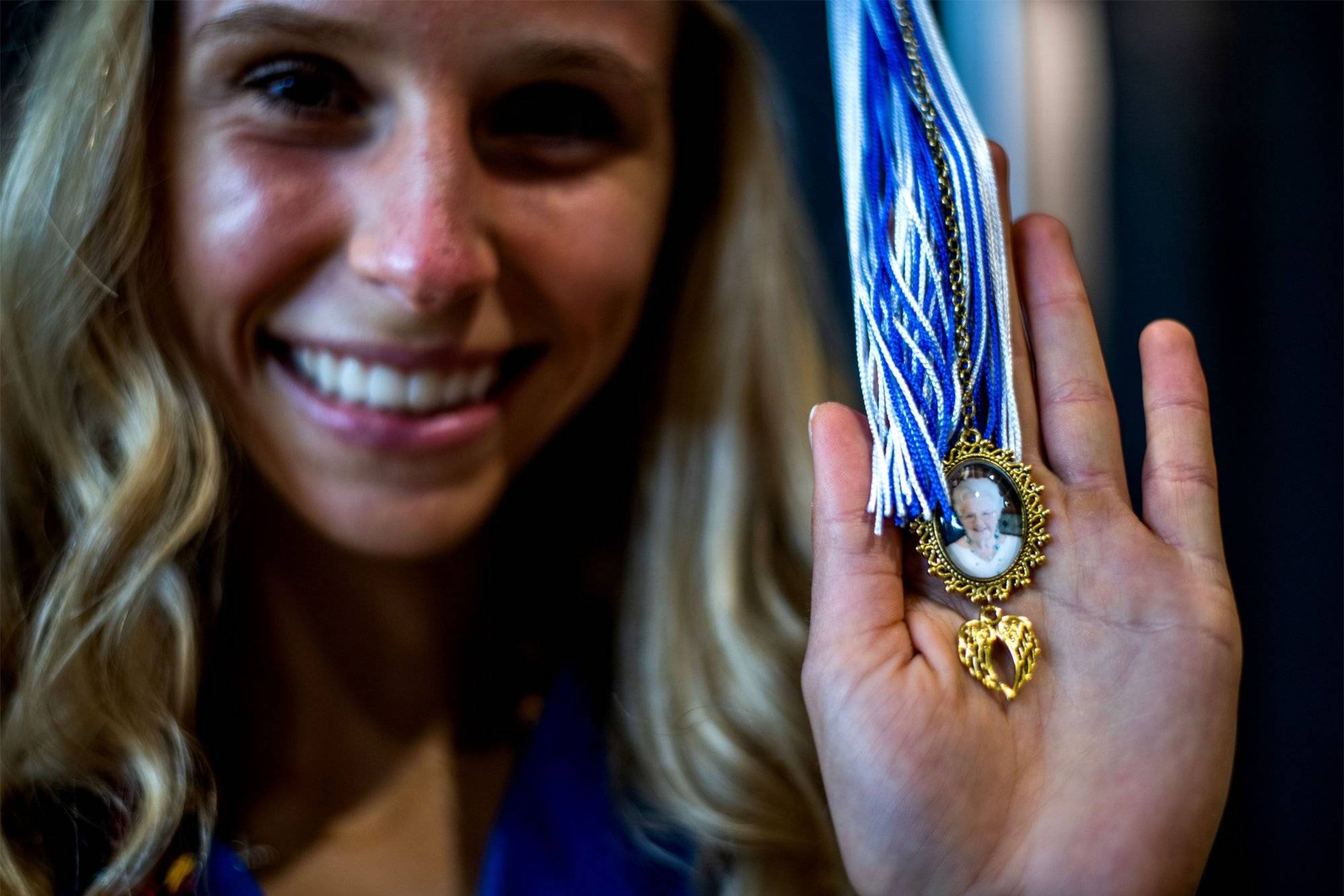 A student poses with a small emblem of her grandmother that hangs from her graduation tassel.